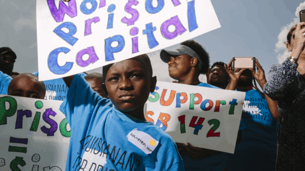 Photo of Black boy holding sign that says World's Prison Capital