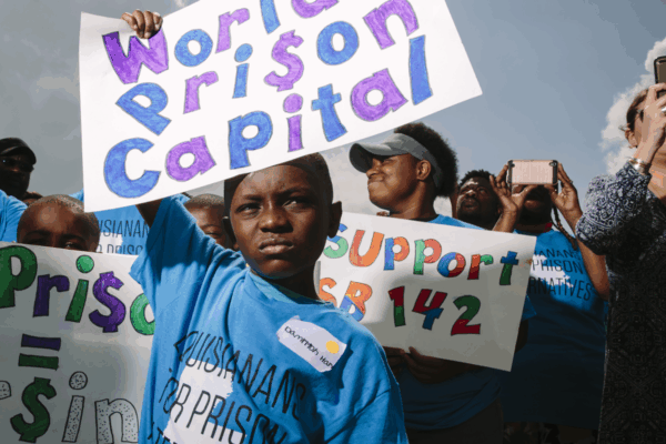 Photo of Black boy holding sign that says World's Prison Capital