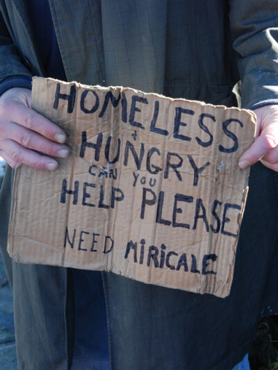 Photo of homeless man holding sign asking for help