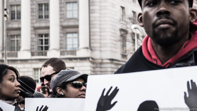 black men and women marchers carrying hands up don't shoot signs