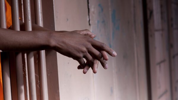 hands of an african-american man held out through prison bars