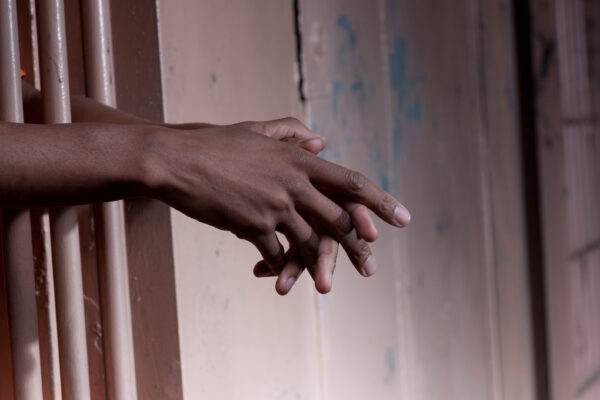 hands of an african-american man held out through prison bars