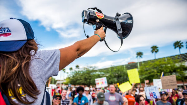 Student holding up a megaphone in front of a crowd