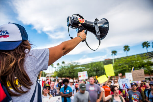 Student holding up a megaphone in front of a crowd