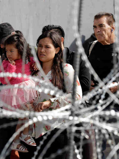A line of immigrants behind a barbed wire fence
