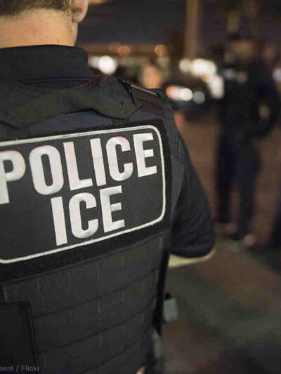 Officer wearing a flak jacket that reads "Police ICE"