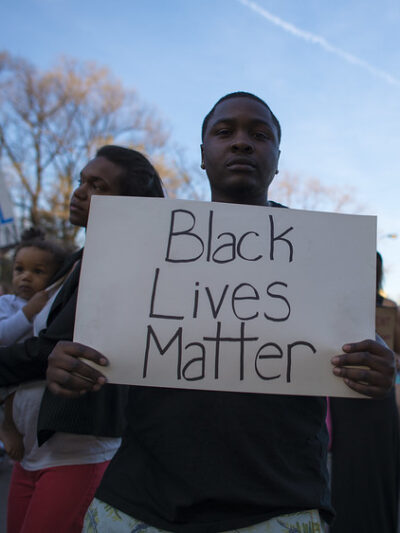Young African American man holding a sign that reads Black Lives Matter