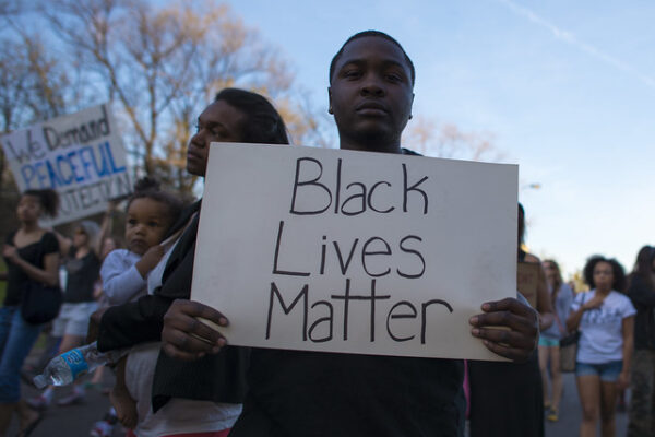 Young African American man holding a sign that reads Black Lives Matter