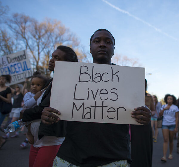Young African American man holding a sign that reads Black Lives Matter