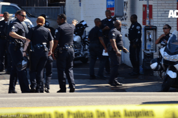 a group of police officers gathers outside a convenience store