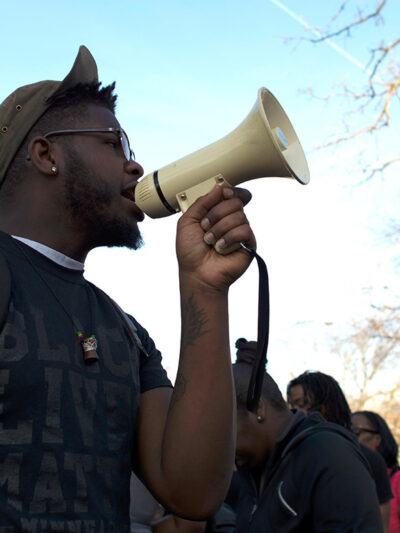 A black man holds a bullhorn at a protest