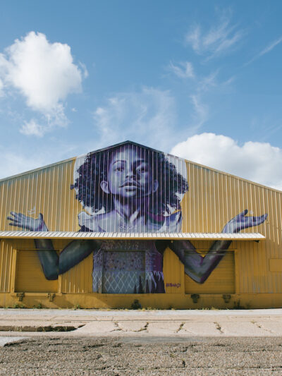 The exterior of BMike's Studio Be, with a mural of a young Black girl with her arms outstretched