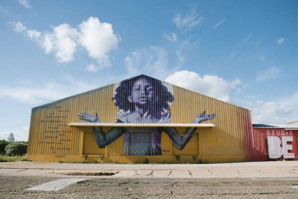 The exterior of BMike's Studio Be, with a mural of a young Black girl with her arms outstretched