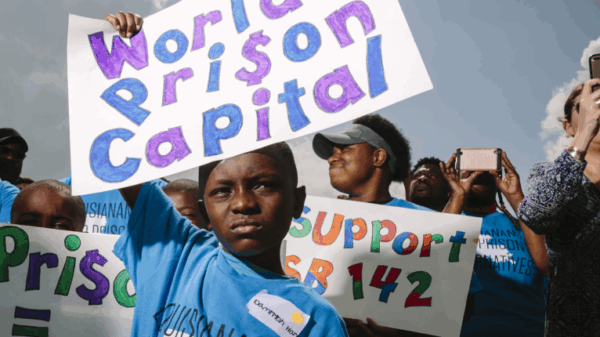 A boy holds a rally sign that reads "World's Prison Capital"