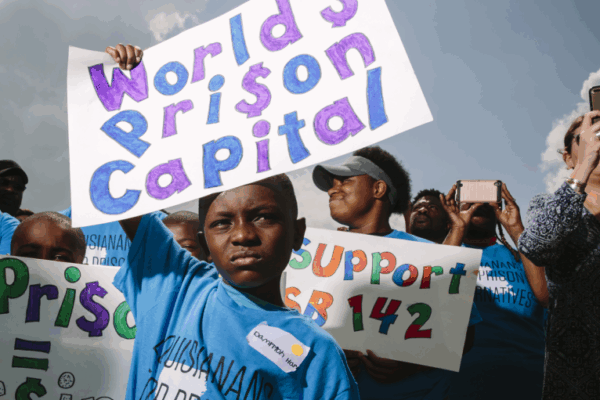 A boy holds a rally sign that reads "World's Prison Capital"