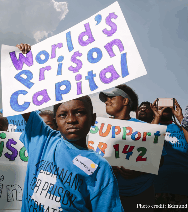 A boy holds a rally sign that reads "World's Prison Capital"