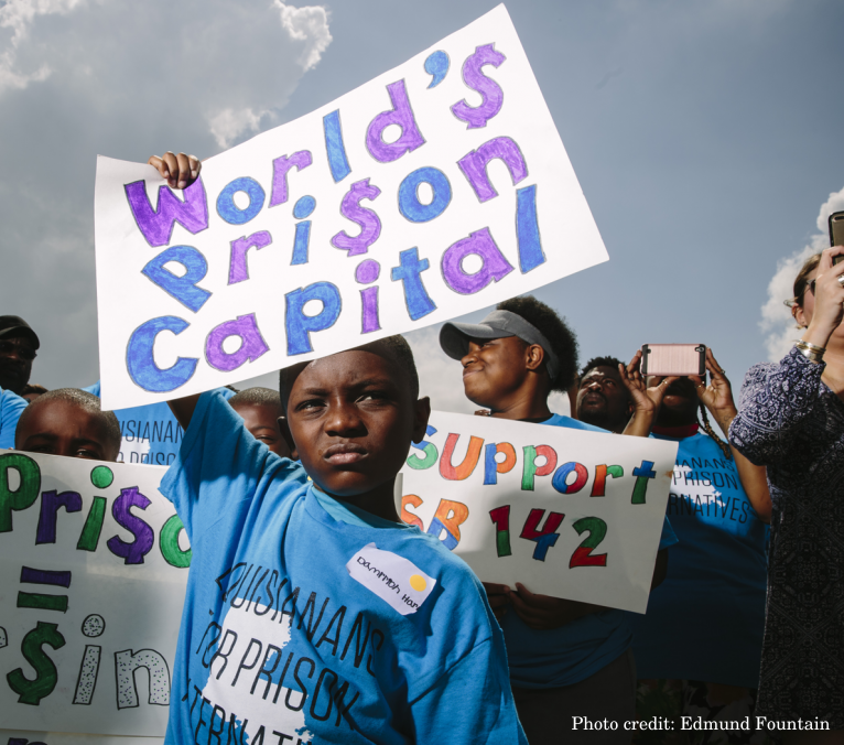 A boy holds a rally sign that reads "World's Prison Capital"