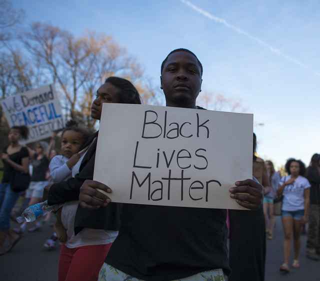 Young African American man holding a sign that reads Black Lives Matter 