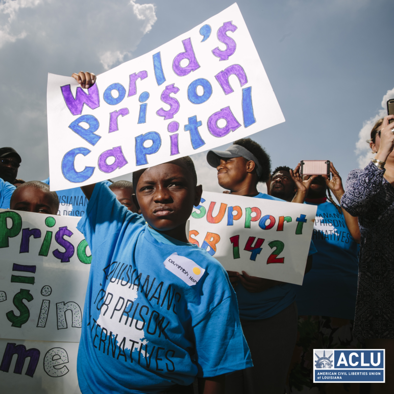 Photo of Black boy holding sign that says World's Prison Capital