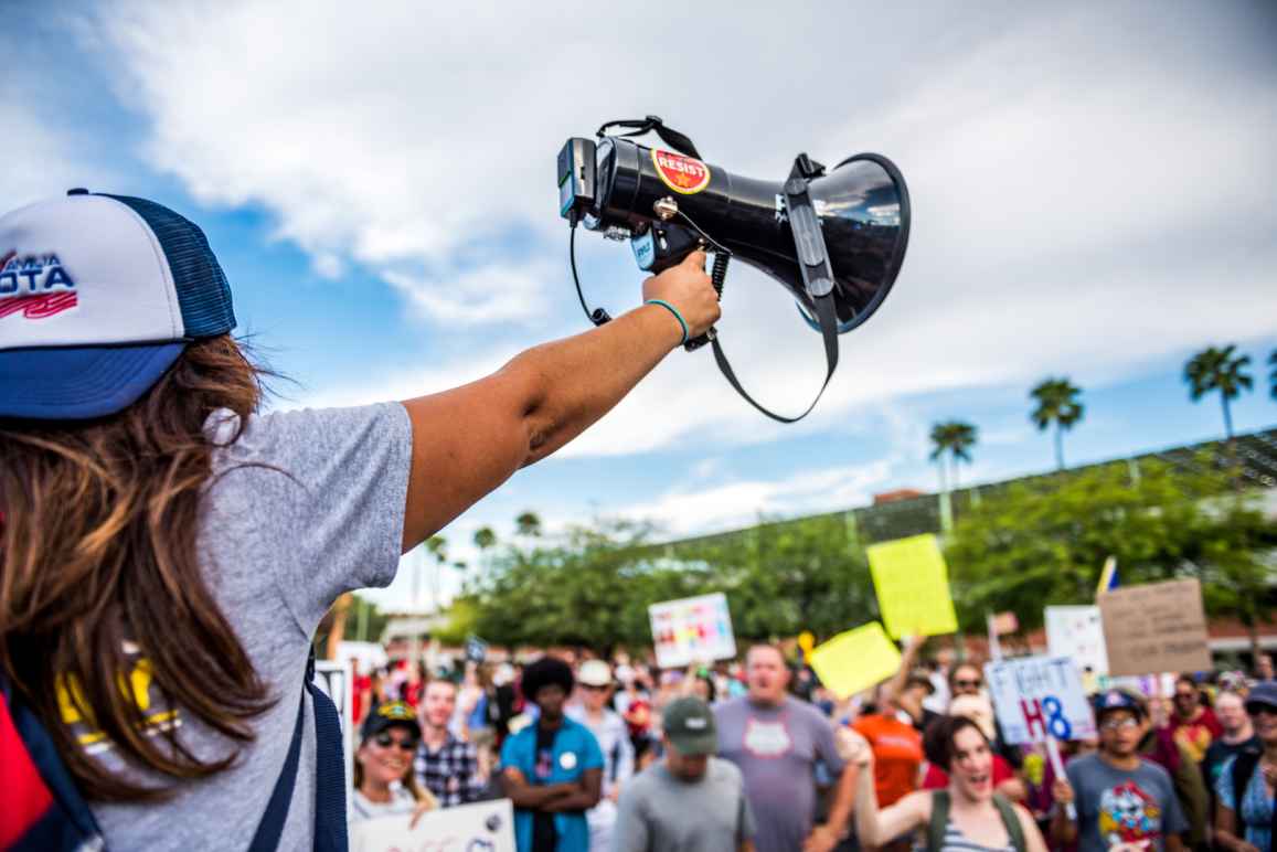 Student holding up a megaphone in front of a crowd 