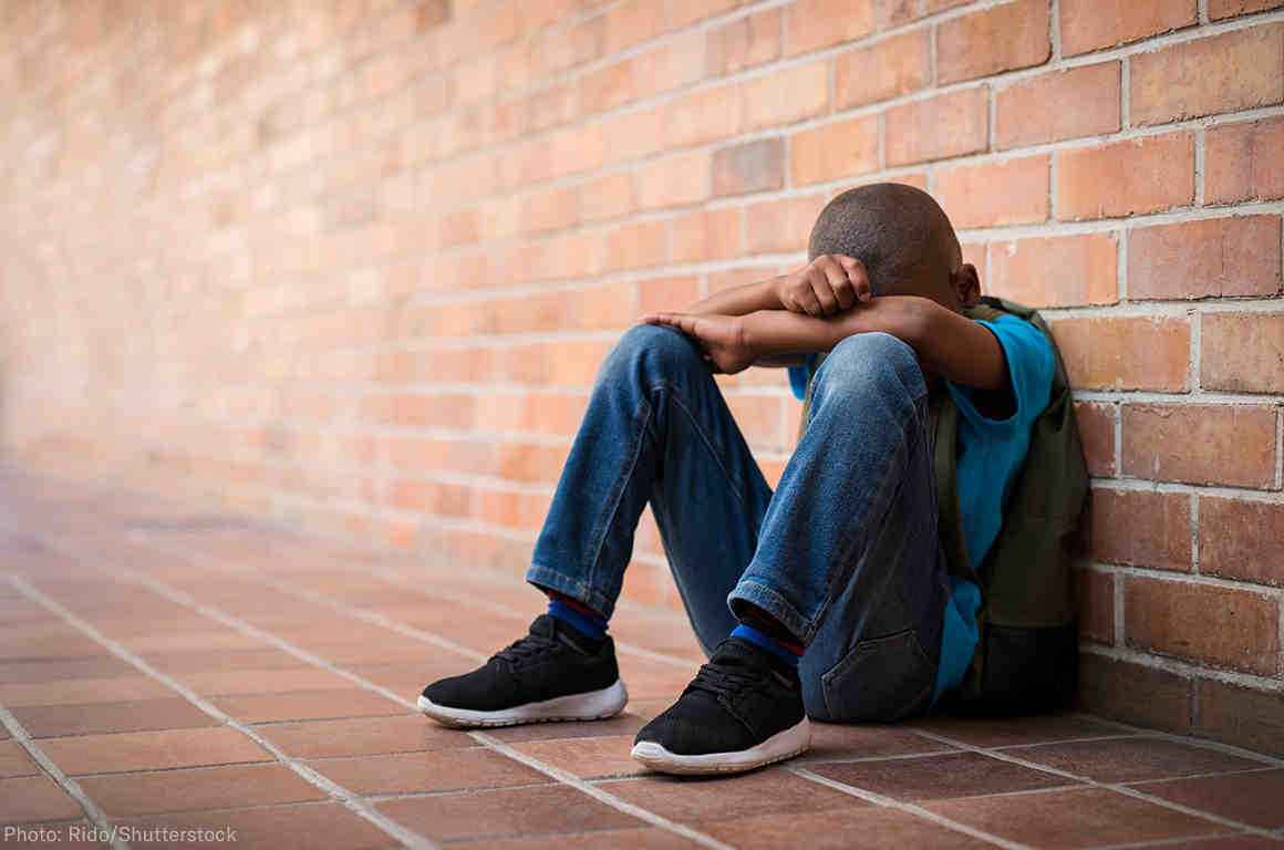 A Black student with his head between his hands