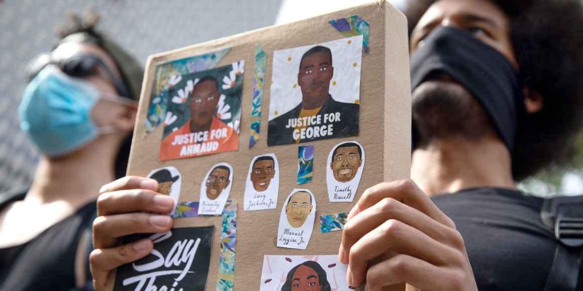 Photo of protesters holding up a sign memorializing George Floyd and others