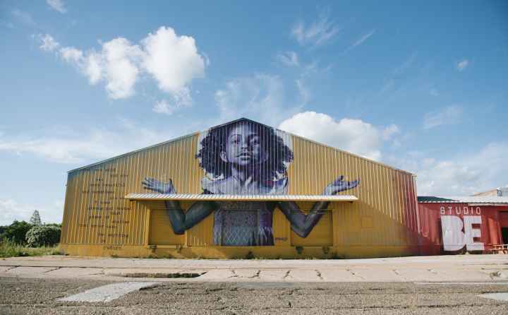 The exterior of BMike's Studio Be, with a mural of a young Black girl with her arms outstretched