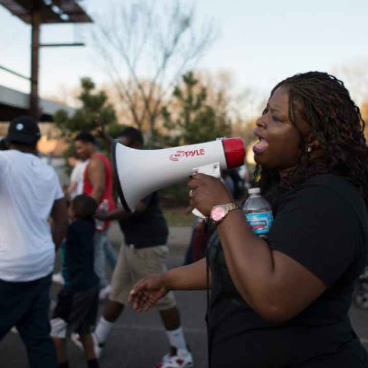 A Black woman speaking into a bullhorn at a protest