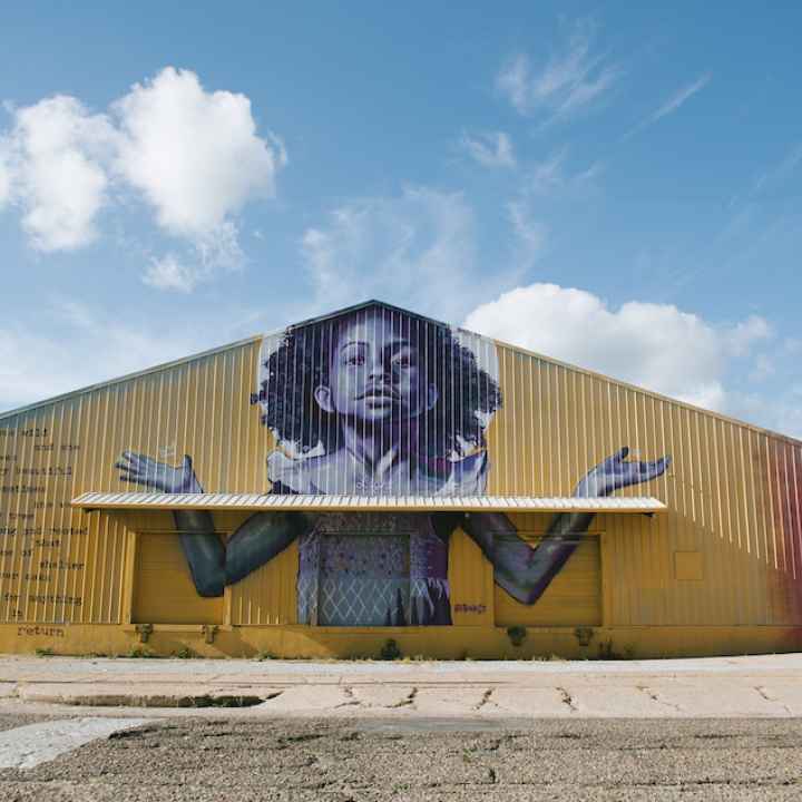 The exterior of BMike's Studio Be, with a mural of a young Black girl with her arms outstretched
