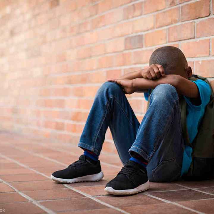 A Black student with his head between his hands