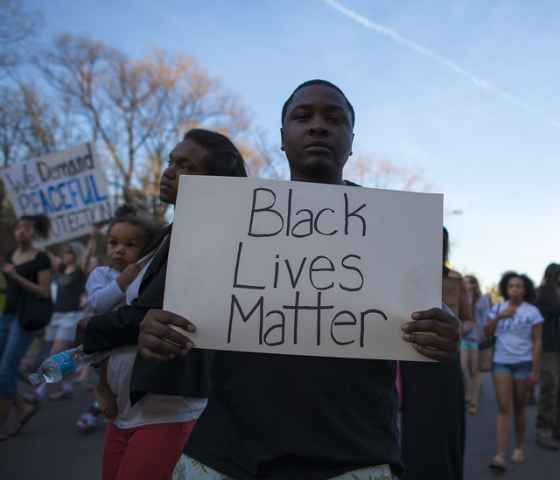 Young African American man holding a sign that reads Black Lives Matter 