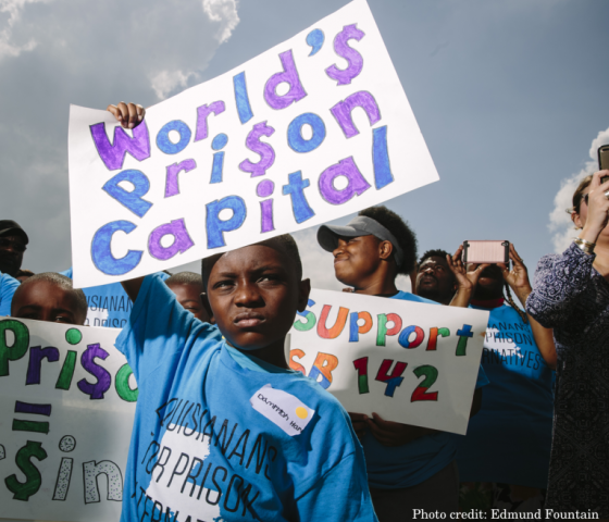 A boy holds a rally sign that reads "World's Prison Capital"
